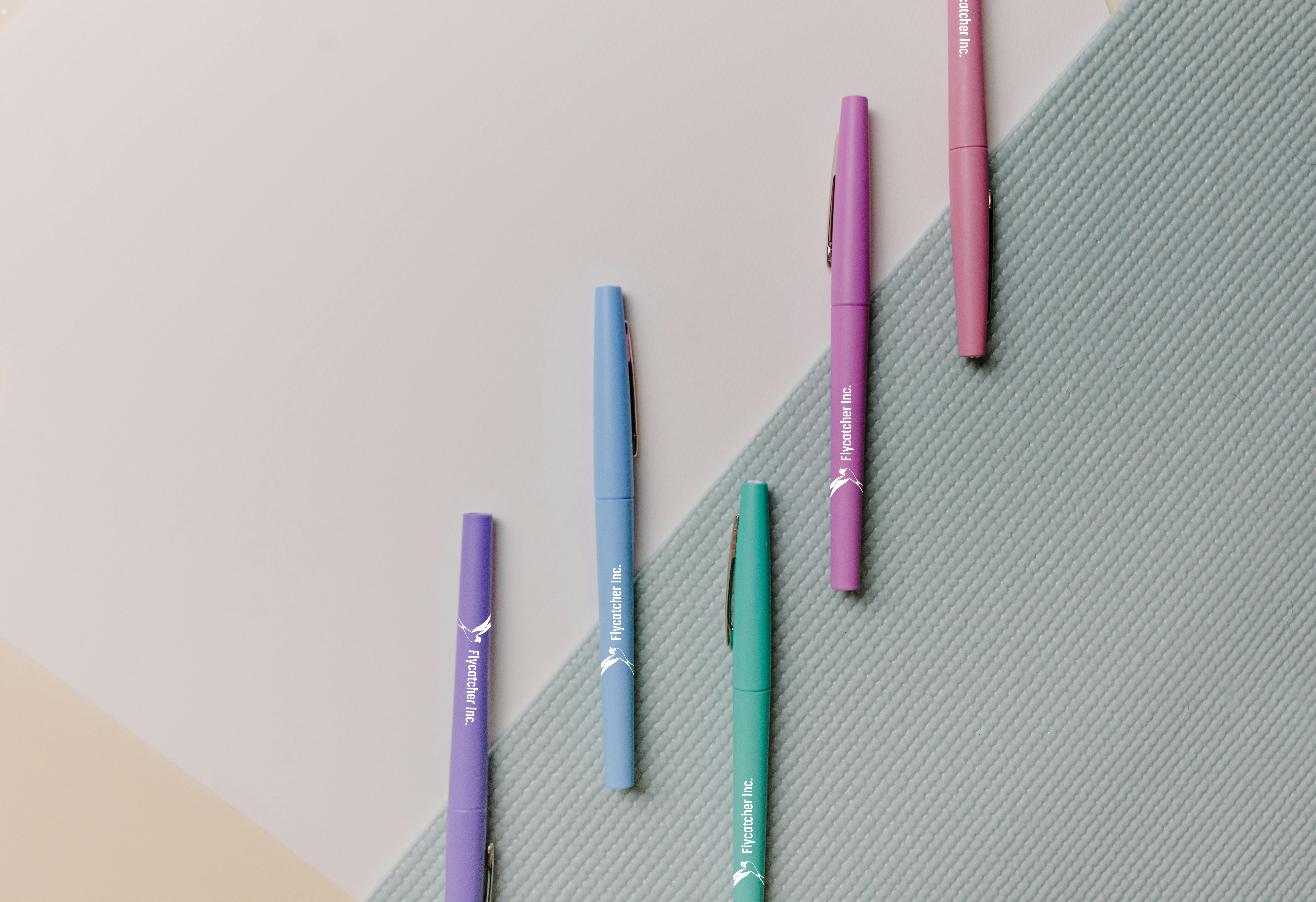 Color pens featuring brand logos on a textured background